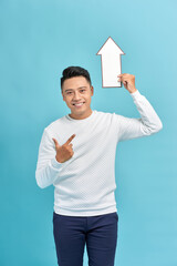 Wall Mural - young man raises white arrow isolated on blue