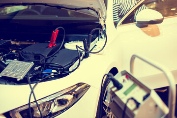 Wall Mural - Selective focus to battery cable connector with blurry car charger machine for maintenance service. Automotive power processing for maintenance car in service center.