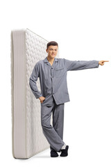 Sticker - Male teenager in pajamas with a bed mattress standing and pointing to the side