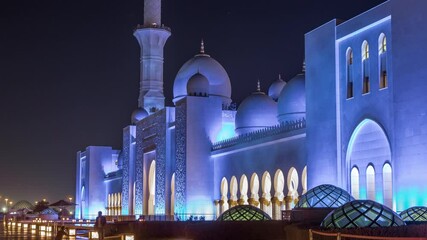 Wall Mural - Sheikh Zayed Grand Mosque illuminated at night timelapse, Abu Dhabi, UAE. Side view with reflections. The 3rd largest mosque in the world