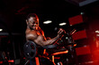 Strength workout. Determined fit man exercising with dumbbells pumping muscles over dark gym background.