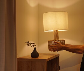 Man placing a decorative electric lamp with warm light in the corner of a room