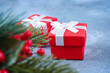Christmas gifts in red boxes on blue concrete background, soft focus of decorative fir branch. Card, New Year, invitation concept. Close-up, copy space.