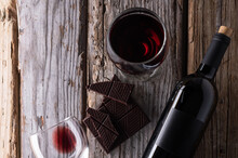 View From Above Of Elegant Bottle And Wineglasses Of Red Wine With Dark Chocolate On Rustic Wooden Background. Wine And Dessert. Template Concept For Your Design And Advertising Company Promotion.