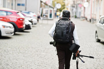 Young professional african american videographer holding professional camera with tripod pro equipment. Afro cameraman wearing black duraq making a videos.