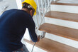 A construction worker applies varnish on the stairs. Using an airbrush for the application. Renovation or finishing works.