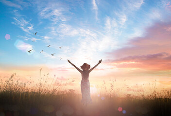 Wall Mural - Silhouette of healthy woman raised hands for praise and worship God at autumn sunset meadow background