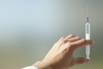 Wall Mural - Doctor's hand holds a syringe with a needle in which the medicine is drawn