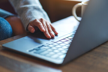 Closeup image of a woman working and touching on laptop computer touchpad on the table