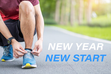 New Year New Start with Young man tying shoelace in the park outdoor, athlete runner man ready for running and jogging in morning. Fitness, wellness, healthy lifestyle and New You concepts