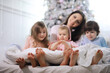 © alexkich - A family with children having fun on the bed under the covers during the Christmas holidays.