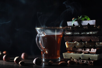 A bar of milk chocolate. Homemade milk chocolate with almonds and dried strawberries. Pieces of milk chocolate. Set of milk chocolate with tea.