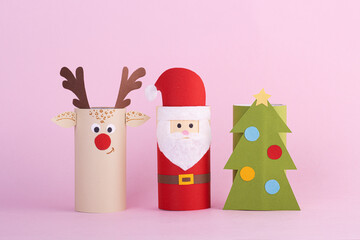 Christmas toys from a toilet tube roll on a pink background. Santa, reindeer and Christmas tree