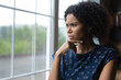 © fizkes - Unhappy young african ethnicity woman looking out of window, thinking of life problems, copy space. Frustrated lost in thoughts millennial mixed race lady feeling doubtful making difficult decision.