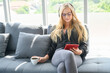 © chokchai - Young woman with glasses sit on sofa and looking at her tablet. Working woman is working at home with relax and casual during work from home.
