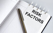 © Iryna - text RISK FACTORS on the short note texture background with pen