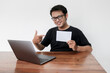 © Reezky - Young Asian man feeling happy with laptop and holding empty white space paper. Smile Indonesia Man wear black shirt Isolated grey background.