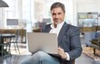 © nyul - Businessman sitting in office working with laptop computer. Business portrait of older man.