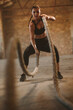 © Jacob Lund - Tough woman working out with battle rope in old warehouse