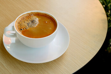 Cup of Hot Coffee with Frothy Surface Isolated on a Round Shaped Wooden Table	