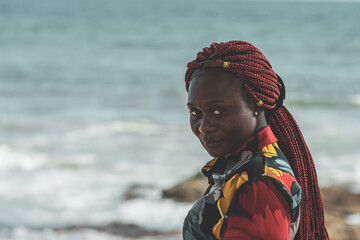 Wall Mural - African woman with rasta hair with attached small ghana flags on the Accra coast Ghana