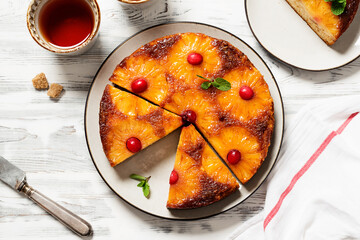 Wall Mural - Homemade pineapple upside down pie with candied cranberry . Tropical dessert on white wooden background . Top view.