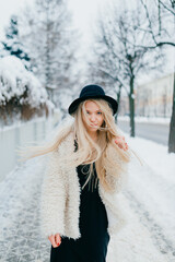 Wall Mural - Stylish blonde girl with long flying hair posing in the street