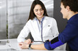 © rogerphoto - Young woman-doctor is checking her patient's blood pressure, while they are sitting together at the desk in a cabinet. Physician at work in a hospital. Medicine and healthcare concepts