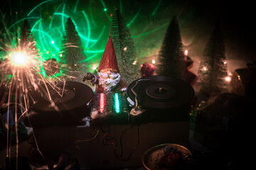 Wall Mural - Dj mixer with headphones on dark nightclub background with Christmas tree New Year Eve. Close up view of New Year elements on a Dj table. Holiday party concept. Empty space