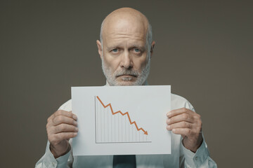 Sad businessman holding a negative financial chart