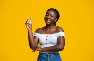 Cheerful Black Woman Showing Peace Gesture While Posing Over Yellow Background