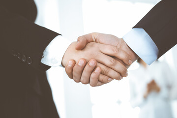 Businessman and woman shaking hands in office. Concept of handshake as success symbol in business