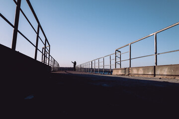 silhouette of person walking on bridge