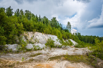 Abandoned talc quarry overgrown with trees and grass