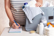 Unrecognizible pregnant caucasian woman in striped t-shirt packing big blue diaper bag to maternity hospital. Diapers, nappy, hat, bottle and other necessary things for newborn baby.