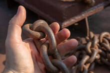 Close-up Of A Sailor's Hand. A Sailor Holds A Metal Mooring Chain In His Hand. Securing The Ship With A Large Chain. Old Rusty Vintage Mooring Bollard For Boats, Ships And Yachts.