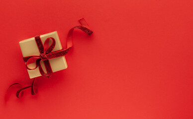 Festive concept with gift box on red background. Top view, copy space.