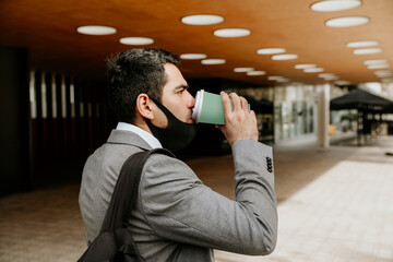 Successful young businessman walking and drinking coffee. Outdoor.