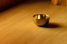 Small Golden Brass Singing Bowl On A Wooden Table