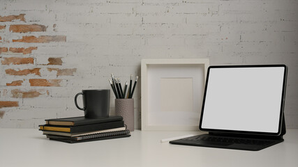Home office desk with tablet, stationery, mock up frame and copy space