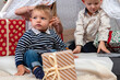 © ako-photography - happy children sit between Christmas gift boxes and toys in a decorated house