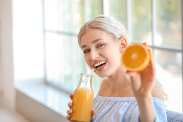 Poster - Beautiful young woman drinking orange juice at home