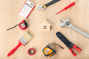 Model of house with supplies on wooden background