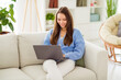 © deagreez - Portrait of attractive cheerful focused girl sitting on divan using laptop web chatting studying in light flat house apartment indoor