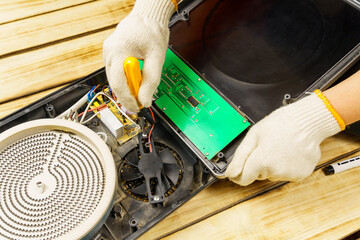 The master unscrews or screws the fan to the electric stove with a screw.