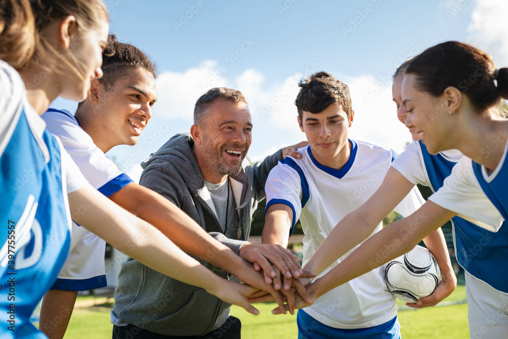 Team of young football players stacking hands before match - obrazy, fototapety, plakaty 