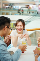 Wall Mural - Pretty young Asian woman drinking iced tea when meeting with friends in cafe