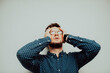 © FarukPhotography - a stressed caucasian businessman wearing a blue shirt and prescription glasses grabs his head and gets annoyed in his office.