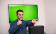 © FarukPhotography - young caucasian businessman wearing glasses points a finger at someone in front of a smart board with a green screen