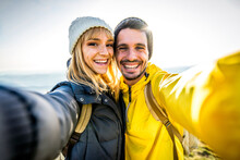 Couple Of Hikers Taking A Selfie Climbing Mountains - Man And Woman With Backpack Smiling At Camera - Bright Filter